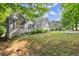 Gray home with an attached garage, bright yellow front door, landscaped front yard, and surrounded by mature trees and greenery at 2730 Samples Rd, Cumming, GA 30041
