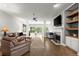 Open-concept living room featuring hardwood floors, a fireplace, comfortable seating, and built-in shelving, bathed in natural light at 2730 Samples Rd, Cumming, GA 30041