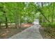 Long concrete driveway leading to a charming home surrounded by lush greenery at 627 Apache Trl, Woodstock, GA 30189