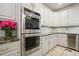 Bright kitchen with white cabinets, double ovens, granite counters, and stainless steel wine cooler at 627 Apache Trl, Woodstock, GA 30189