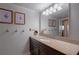 A well-lit bathroom vanity with granite counters, framed botanical art, and vintage style towel hooks at 6851 Roswell Rd # G3, Atlanta, GA 30328