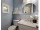 Stylish powder room featuring a marble-topped vanity, round mirror, blue walls, and elegant decor at 2870 Livsey Woods Dr, Tucker, GA 30084