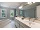 Bathroom featuring double sinks, large mirror, soaking tub, and natural light from the large window at 2870 Livsey Woods Dr, Tucker, GA 30084