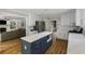 Open-concept kitchen with a blue island, stainless appliances, and white cabinets, seamlessly connecting to the cozy living room at 2870 Livsey Woods Dr, Tucker, GA 30084