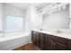 Bathroom featuring a tub, decorative window, double sink vanity, and wood-look flooring at 403 Village Vw, Woodstock, GA 30188