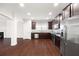Open concept view of a kitchen with stainless steel appliances, hardwood floors, and living room with fireplace at 403 Village Vw, Woodstock, GA 30188