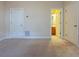 An empty bedroom with neutral colored carpet, multiple doorways, and an air vent on the wall at 275 Autry Mill Ln, Suwanee, GA 30024