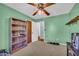 A charming bedroom with light green walls, an open bookshelf and a rustic ceiling fan at 676 Smith Store Rd, Covington, GA 30016