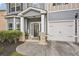 Inviting front porch featuring brick columns, a modern front door, and a well-manicured landscape at 7530 Springbox Dr, Fairburn, GA 30213