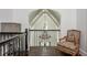A second-story hallway with a decorative chair and railing, showcasing a unique view at 165 Ansley Way, Roswell, GA 30075