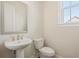 Half bathroom featuring a pedestal sink, elongated toilet, and framed mirror at 2545 Bertrand Way, Cumming, GA 30041