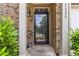 Inviting front entrance with a glass-paneled door, brick facade, and elegant outdoor lighting at 3335 Thornbridge Dr, Powder Springs, GA 30127