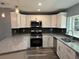 Modern kitchen featuring granite counters, stainless steel appliances, herringbone backsplash, and white cabinetry at 5090 Lorraine Pl, Forest Park, GA 30297