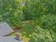 Green backyard surrounded by trees and the roof of the house with chimney on the side at 5632 Stillwater Ct, Stone Mountain, GA 30087