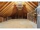Spacious unfinished attic featuring exposed beams, plywood flooring, and natural light, ideal for expansion or storage at 1460 Lakemist Ct, Roswell, GA 30075