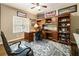 Home office with wood desk, built-in shelving, and a comfortable chair on a patterned rug at 10530 Tuxford Dr, Alpharetta, GA 30022