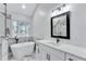 Bright bathroom features a soaking tub next to a large window and white cabinets topped with marble counters at 2169 Wingfoot Pl, Decatur, GA 30035