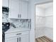 Bright kitchen featuring white cabinets, marble backsplash, and an adjacent pantry for ample storage at 2169 Wingfoot Pl, Decatur, GA 30035