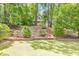 Serene backyard featuring a lush green lawn, mature trees, and a charming view of the home through the foliage at 405 W Leslie Ct, Woodstock, GA 30188