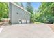 Three-car garage with ample parking space in front of a well-maintained, gray home surrounded by lush greenery at 405 W Leslie Ct, Woodstock, GA 30188
