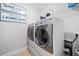 Bright laundry room featuring a modern washer and dryer set with decorative laundry signage and storage shelves at 508 Highland Dr, Woodstock, GA 30188