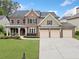 Traditional brick home with a three-car garage, landscaped yard, and covered front porch at 508 Highland Drive Dr, Woodstock, GA 30188