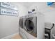 Bright laundry room featuring side-by-side washer and dryer, decorative signs, and a wire rack for storage at 508 Highland Drive Dr, Woodstock, GA 30188