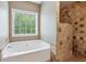 Bright bathroom features a soaking tub under a window and a tiled walk-in shower at 726 Sunset Ridge Ln, Lawrenceville, GA 30045