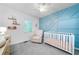 Bedroom with blue accent wall, crib, and comfy chair creates a serene and inviting space at 802 Bluff Pl, Woodstock, GA 30188
