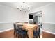 Dining room featuring hardwood floors, chandelier, wainscoting, and access to living room and kitchen at 802 Bluff Pl, Woodstock, GA 30188