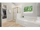 Bright bathroom featuring a soaking tub beneath a window and a glass-enclosed shower with gold trim at 5204 Tealing Ne Dr, Roswell, GA 30075