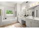 Bright bathroom with a garden tub, double vanity, and large mirror, offering a spa-like experience at 5204 Tealing Ne Dr, Roswell, GA 30075