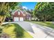 Traditional brick home with a well-manicured lawn, two-car garage, and long driveway at 5204 Tealing Ne Dr, Roswell, GA 30075