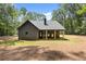 Back exterior featuring wood columns, fireplace, and beautifully manicured lawn and wooded backdrop at 1687 Harmony Rd, Temple, GA 30179