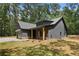 Side view of Craftsman-style home featuring vertical siding, stone accents, and a side entry garage at 1687 Harmony Rd, Temple, GA 30179