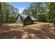 Back exterior featuring wood columns, fireplace, and beautifully manicured lawn and wooded backdrop at 1687 Harmony Rd, Temple, GA 30179