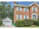 View of the brick home featuring light green shutters, white detached garage, and manicured bushes at 3196 Henderson Walk, Atlanta, GA 30340