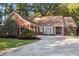 Charming brick home featuring a well-manicured lawn, mature trees, and a circular driveway leading to a double-door entrance at 8900 River Trace Dr, Johns Creek, GA 30097