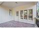 A covered patio with brick floor and access to the home and outdoor space at 8900 River Trace Dr, Johns Creek, GA 30097