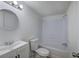 White bathroom features updated vanity, round mirror, and tiled tub and shower at 12208 Buchanan Hwy, Temple, GA 30179