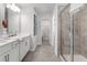 Bright bathroom with double sink vanity, glass shower stall, and doorway to walk-in closet at 206 Maycrest Path, Tucker, GA 30084