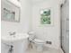 Bathroom features a white pedestal sink, toilet, a glass-door shower and window at 383 Oakridge Dr, Cartersville, GA 30121
