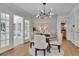 Dining room with hardwood floors, modern light fixture, and views into sunroom and living room at 525 Old Path Xing, Roswell, GA 30075