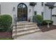 Stunning stone steps lead to an elegant arched front door with wrought iron detailing and tasteful landscaping at 525 Old Path Xing, Roswell, GA 30075