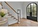 Bright foyer featuring hardwood floors, a grand staircase with a white banister, and an arched glass front door at 525 Old Path Xing, Roswell, GA 30075