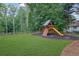 Well-maintained backyard with a playset, lush green grass, and privacy provided by the surrounding trees at 525 Old Path Xing, Roswell, GA 30075