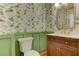 Stylish powder room with vibrant floral wallpaper, green wainscoting, and a wood vanity at 4259 Arbor Club Dr, Marietta, GA 30066