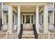 Inviting front porch with white columns, brick steps, black railing, and seating area at 105 Cumming St, Alpharetta, GA 30009