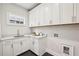 Bright laundry room featuring white cabinetry, quartz countertops, and modern fixtures at 105 Cumming St, Alpharetta, GA 30009
