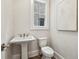 Stylish powder room with pedestal sink, toilet, and decorative mirror, offering a convenient space at 105 Cumming St, Alpharetta, GA 30009